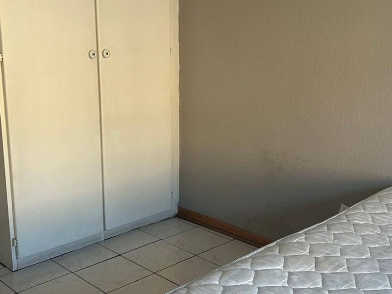 A bedroom featuring tiled flooring and a built-in wardrobe, currently vacant and requiring minor cosmetic attention to the walls and finishes.