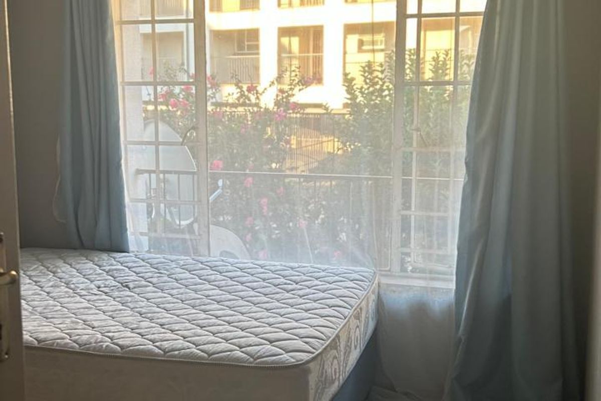 A bedroom featuring tiled flooring and a large window that allows for natural light.