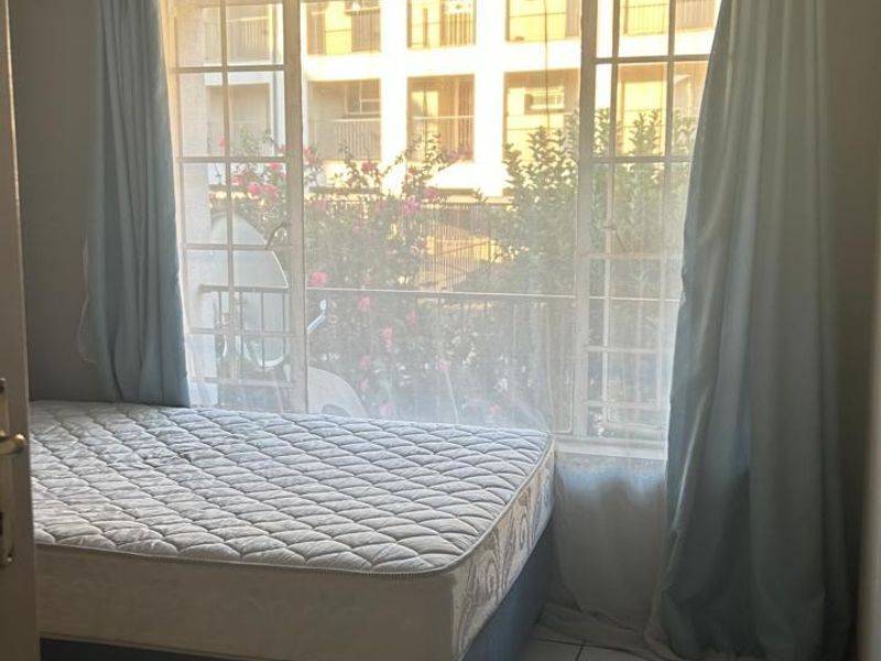 A bedroom featuring tiled flooring and a large window that allows for natural light.