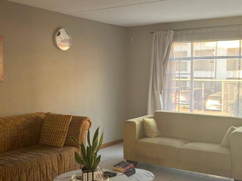 A living room featuring tiled flooring, a large window allowing natural light, and a ceiling-mounted light fixture.