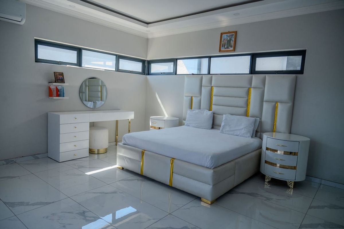 Modern bedroom featuring high-gloss porcelain tile flooring, recessed ceiling detail, and clerestory windows providing natural light.