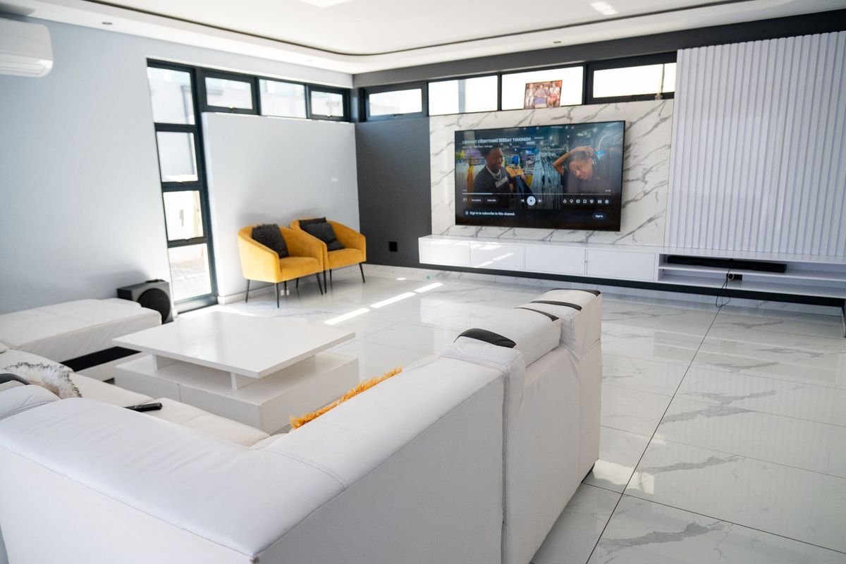 Modern living room featuring high-gloss marble-look floor tiles, a sleek built-in media console with a marble feature wall, and recessed ceiling lighting.
