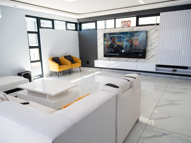 Modern living room featuring high-gloss marble-look floor tiles, a sleek built-in media console with a marble feature wall, and recessed ceiling lighting.