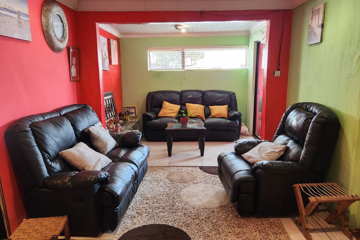 A living room featuring tiled flooring, decorative ceiling tiles, and recessed lighting, currently finished with bold red and green wall paint.