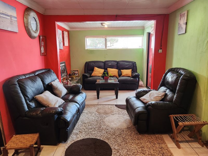 A living room featuring tiled flooring, decorative ceiling tiles, and recessed lighting, currently finished with bold red and green wall paint.