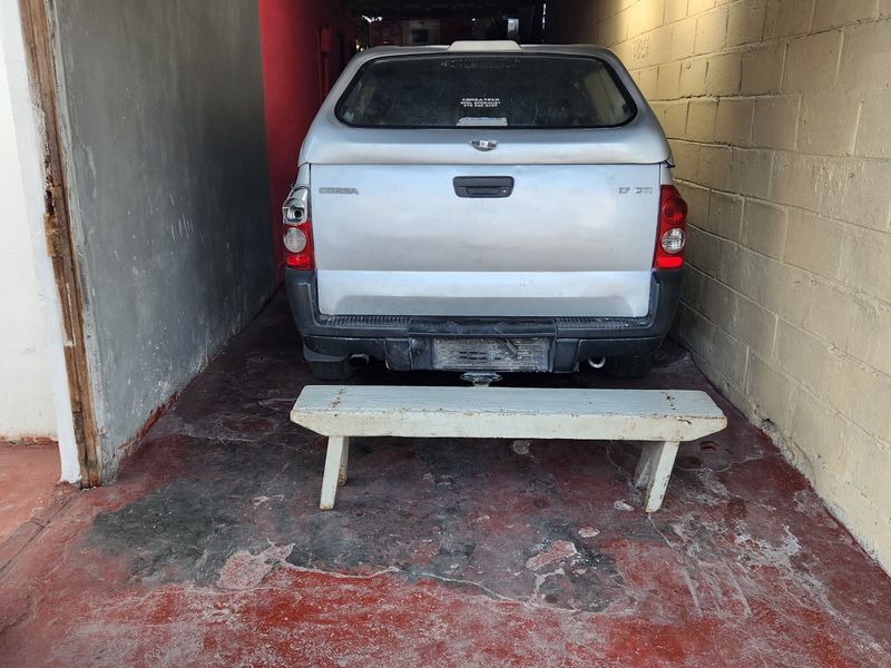 A functional garage space featuring concrete block walls, a corrugated roof, and a painted concrete floor, providing basic covered parking or storage.