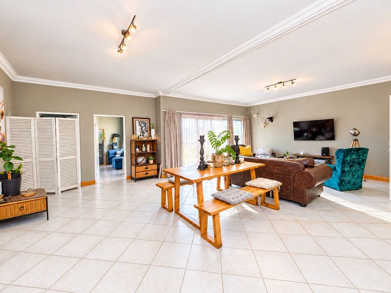 Spacious open-plan living and dining area featuring neutral wall tones, tiled flooring, and decorative crown molding throughout the space.