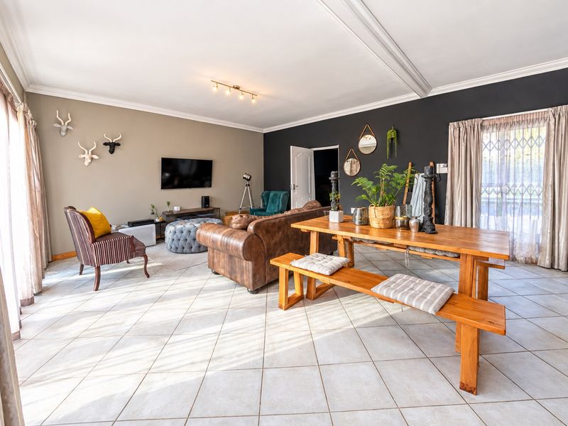 Spacious open-plan living and dining area featuring neutral tiled flooring, a recessed ceiling, and direct access to the exterior through a security gate.