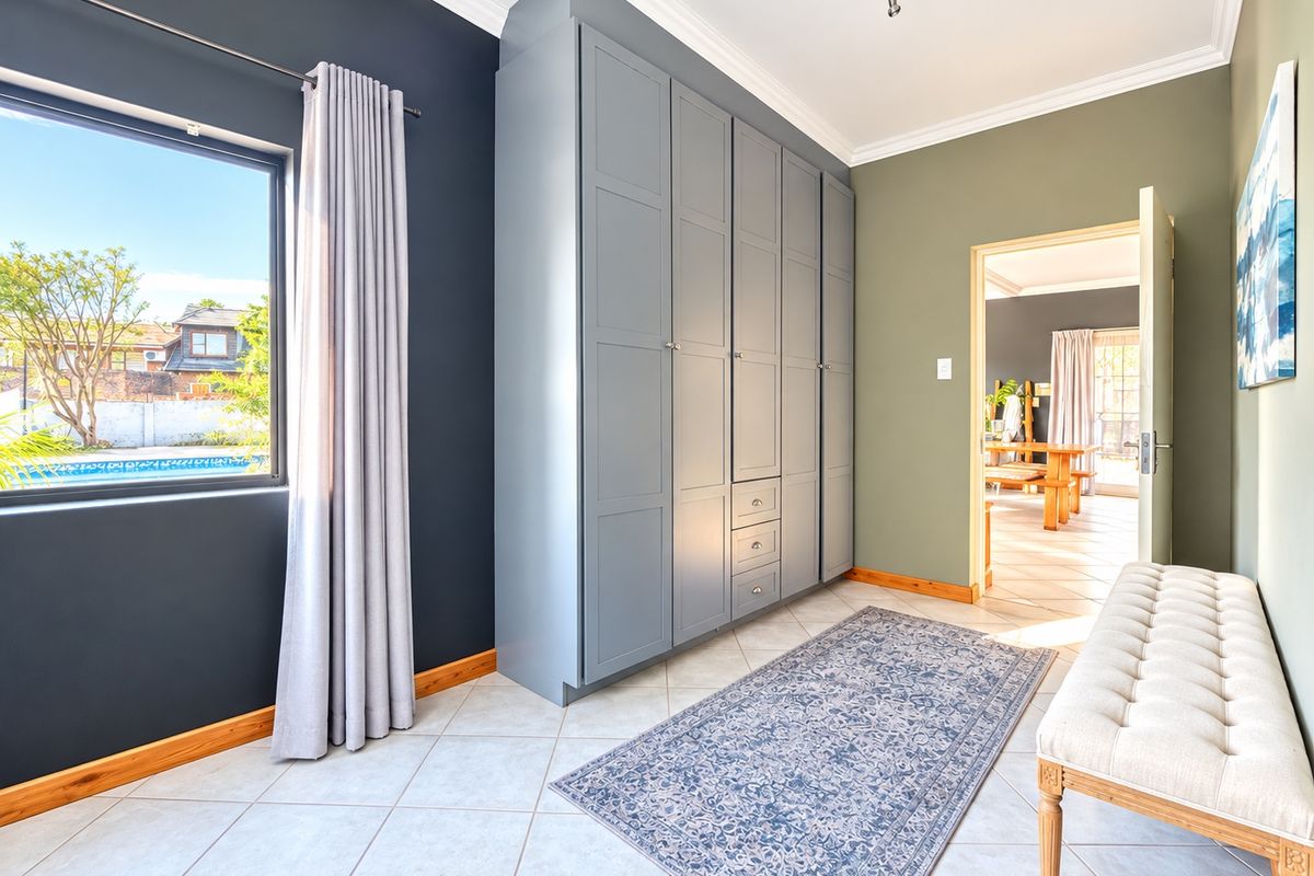 A well-maintained bedroom featuring built-in cabinetry, tiled flooring, and crown molding, with a view overlooking the pool area.