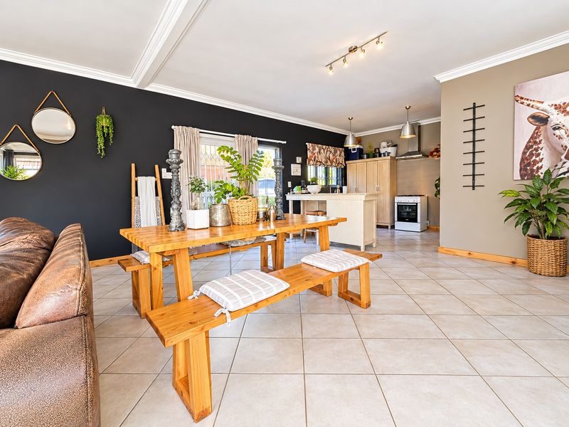 Spacious open-plan living and dining area featuring tiled flooring, crown molding, and a functional kitchen with built-in cabinetry and a freestanding stove.