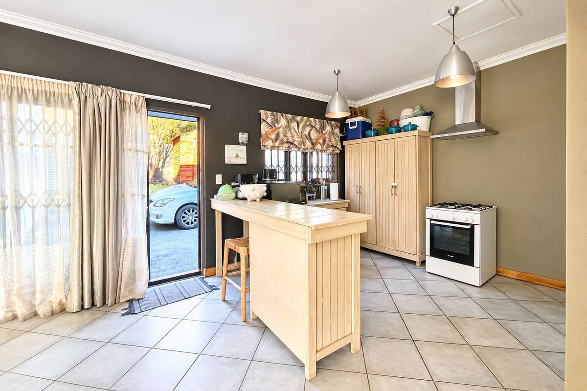 Functional kitchen area featuring tiled flooring, a freestanding stove with extractor fan, and direct access to the exterior through a sliding glass door.
