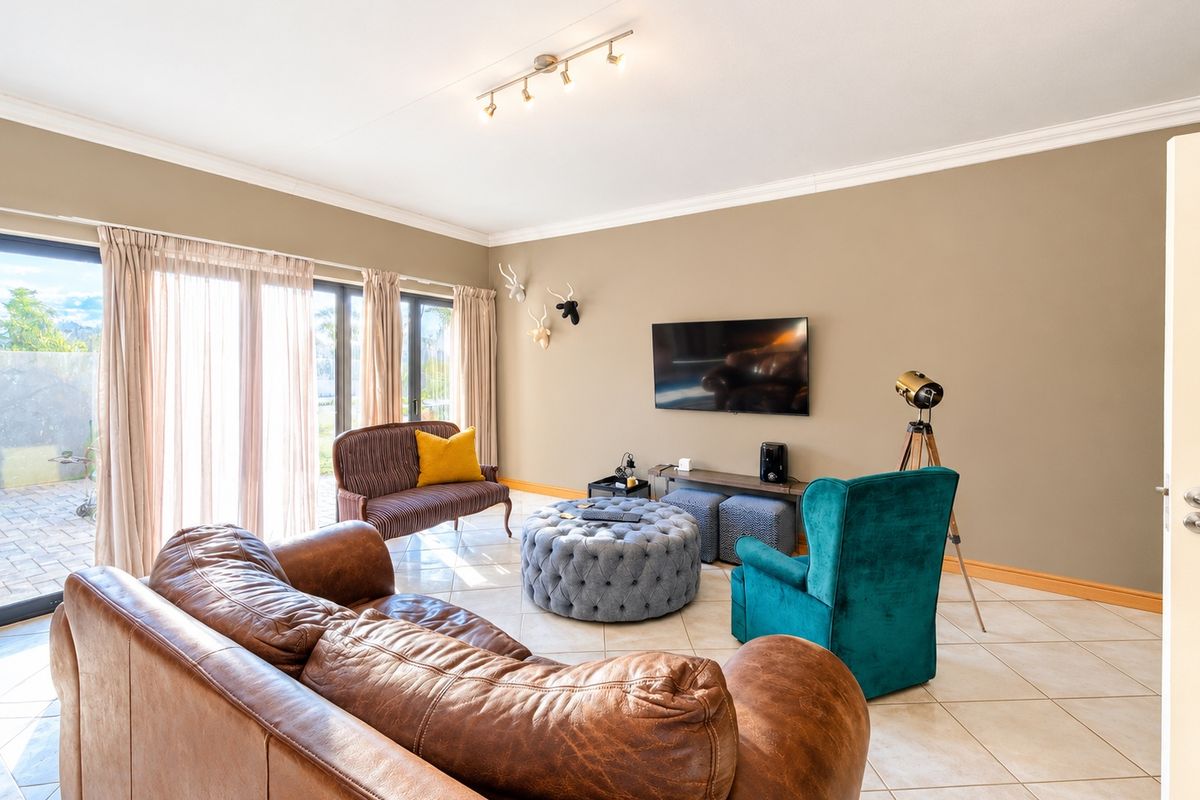 Spacious living room featuring neutral walls, tiled flooring, crown molding, and large sliding glass doors providing access to the outdoor area.