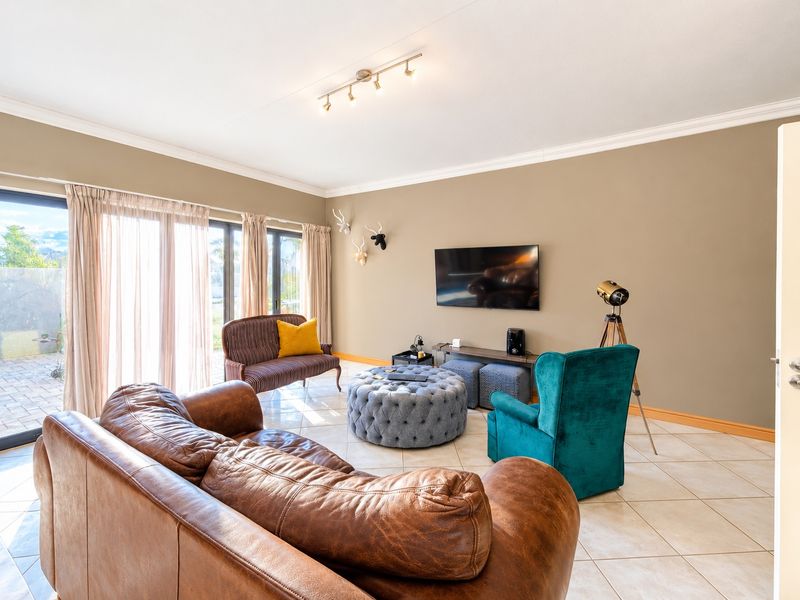 Spacious living room featuring neutral walls, tiled flooring, crown molding, and large sliding glass doors providing access to the outdoor area.