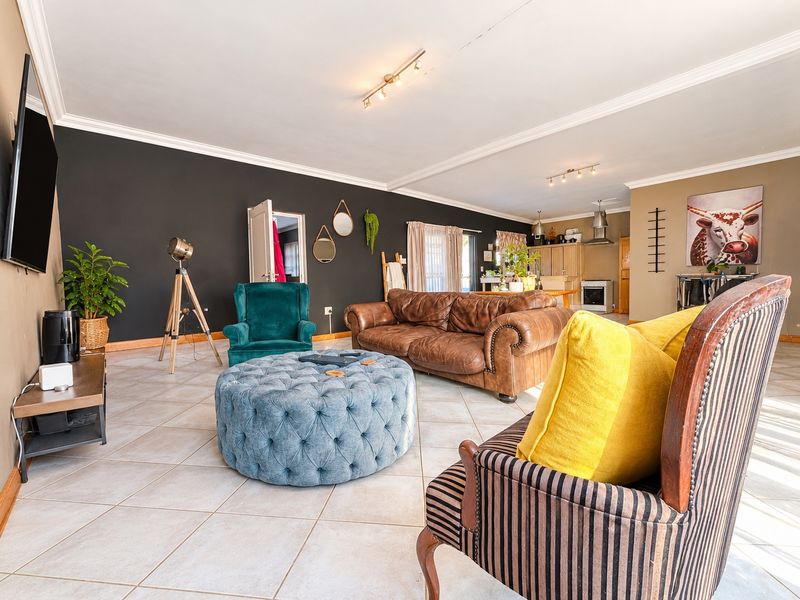 Spacious open-plan living area featuring tiled floors, crown molding, and a connected kitchen space with built-in cabinetry and a stove.