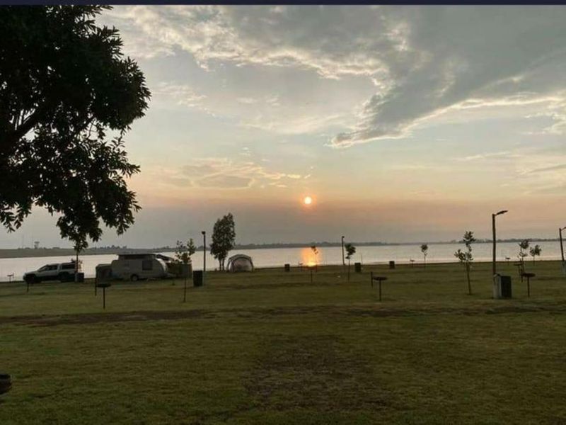 A scenic view of the farm property featuring a large open lawn area overlooking a tranquil lake at sunset.