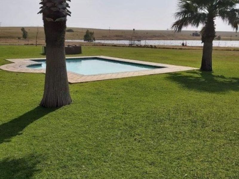 Outdoor swimming pool area set within a spacious, well-maintained lawn with scenic landscape views.