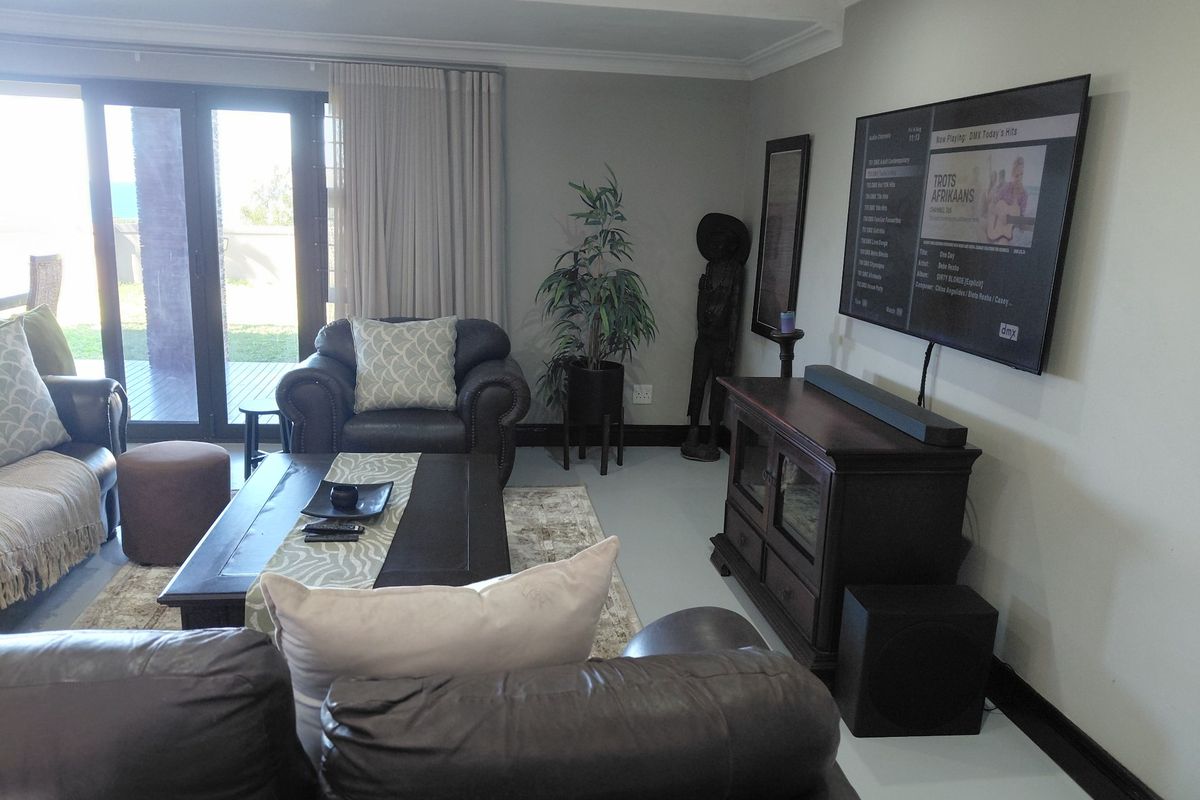 A comfortable living room featuring neutral walls, cove ceiling detailing, and large sliding glass doors providing access to the outdoor patio area.