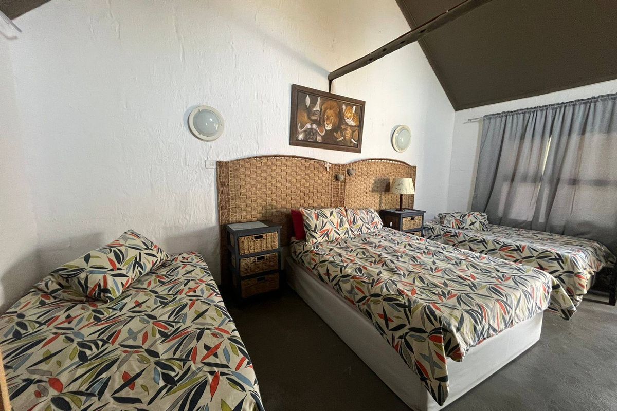 A bedroom featuring a high vaulted ceiling with an exposed structural beam and wall-mounted lighting, providing a rustic and spacious atmosphere.