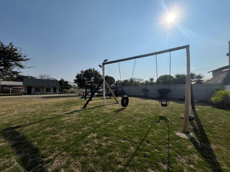 Spacious outdoor garden area featuring a swing set and perimeter precast concrete walling, suitable for recreational use.