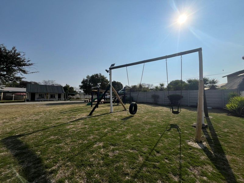 Outdoor recreational area featuring a swing set and a well-defined lawn enclosed by a precast concrete boundary wall.