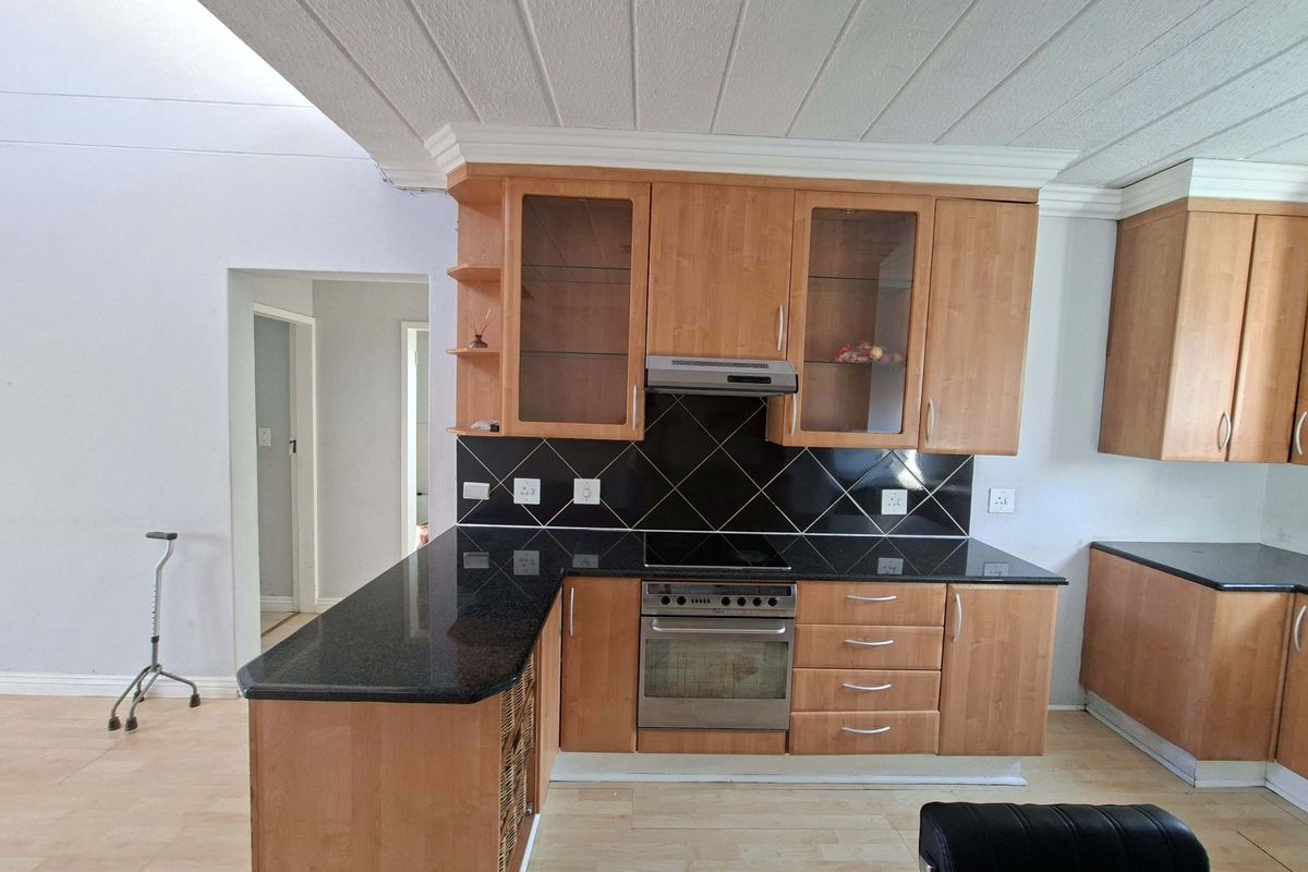 A functional kitchen featuring wooden cabinetry, granite countertops, a built-in electric stove with oven, and a tiled backsplash.