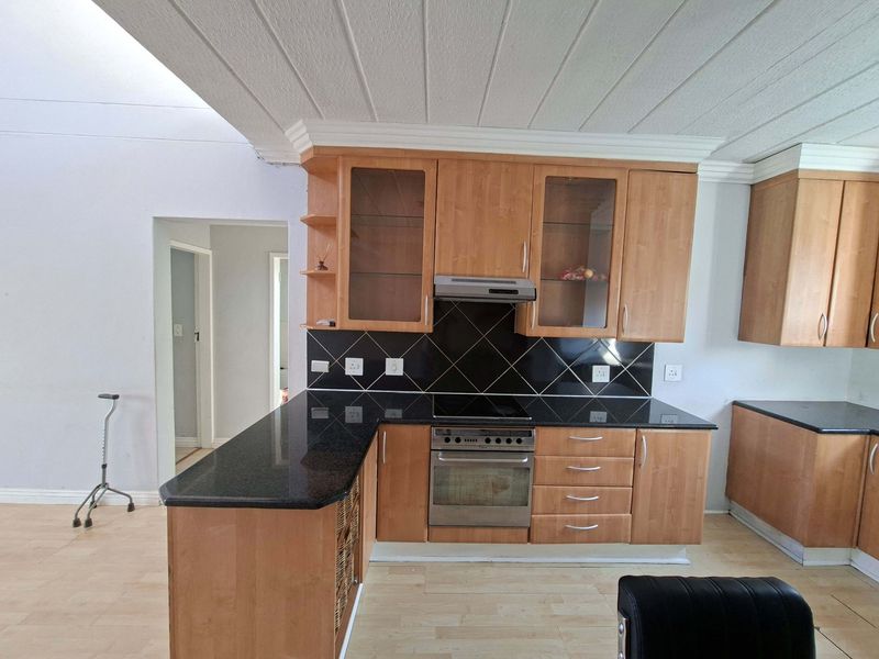 A functional kitchen featuring wooden cabinetry, granite countertops, a built-in electric stove with oven, and a tiled backsplash.
