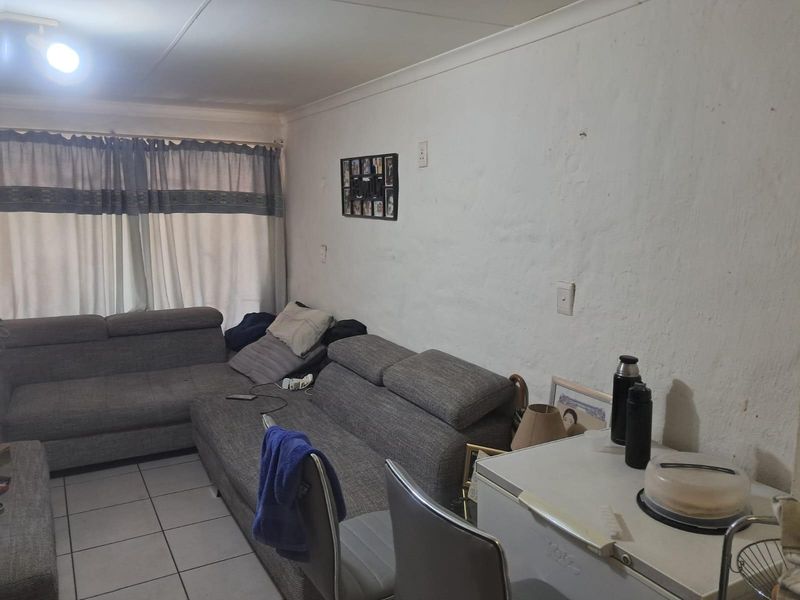 A living room area featuring tiled flooring and coved ceilings, requiring cosmetic updates to the wall finishes to improve the overall aesthetic.