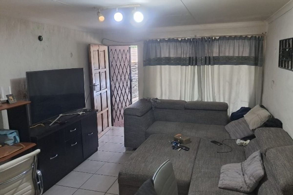 A living room area featuring tiled flooring, track lighting, and a security gate leading to the exterior.