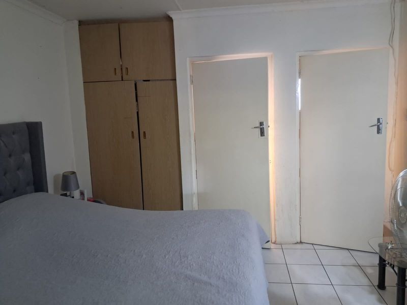 A bedroom featuring built-in wooden cupboards and tiled flooring, requiring minor cosmetic updates to improve the overall aesthetic.