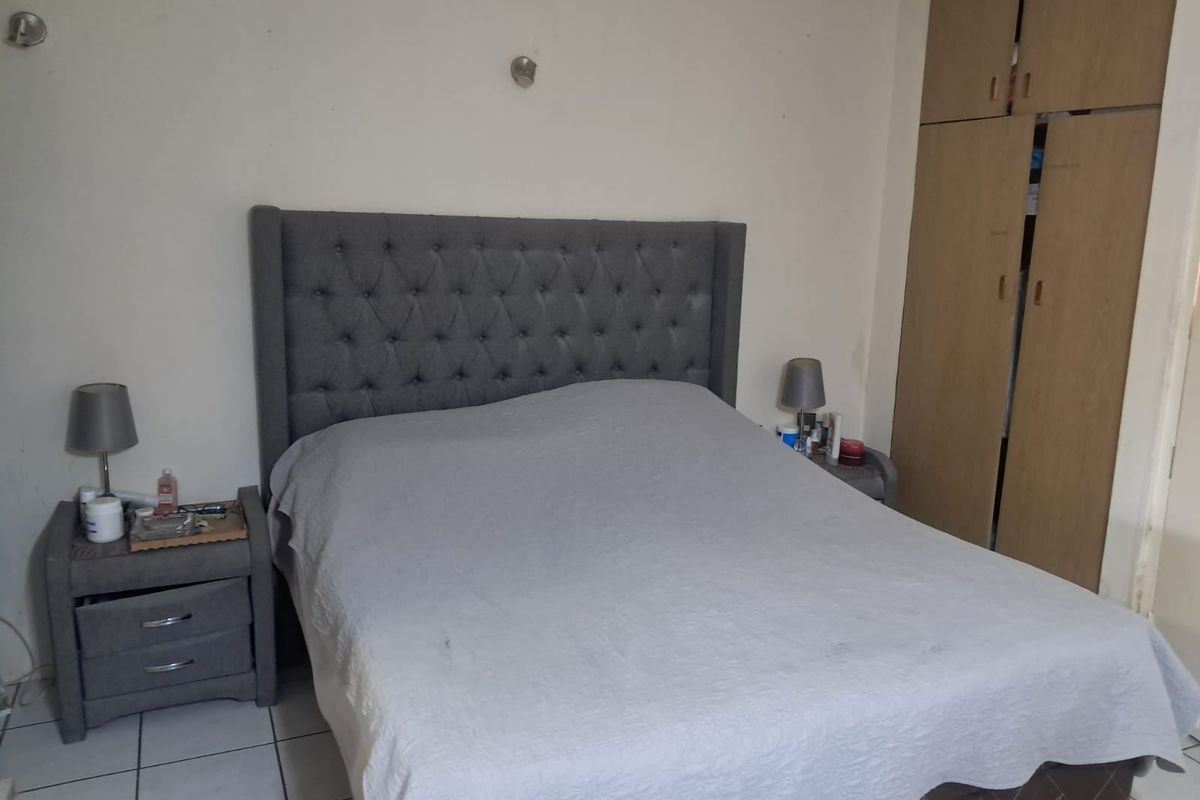 A functional bedroom featuring built-in wooden cupboards and tiled flooring, offering a neutral base for potential interior updates.