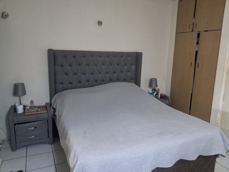 A functional bedroom featuring built-in wooden cupboards and tiled flooring, offering a neutral base for potential interior updates.