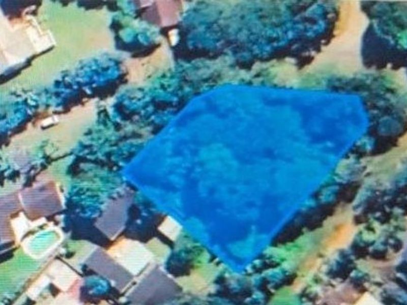 An aerial view highlighting the boundaries of a vacant residential land plot situated within an established neighborhood.