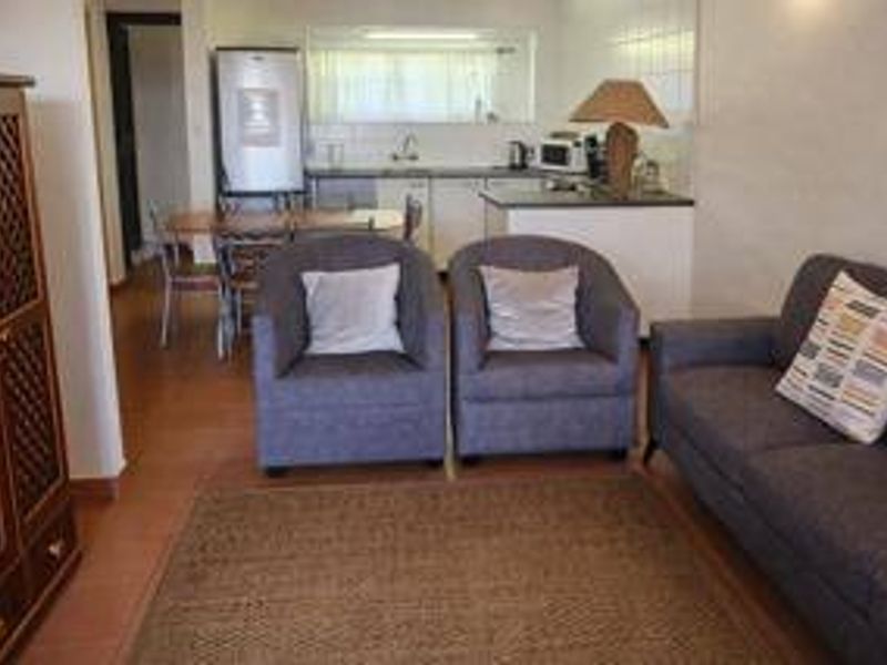 Open plan living and kitchen area featuring tiled flooring and a functional kitchen layout with a pass-through window.