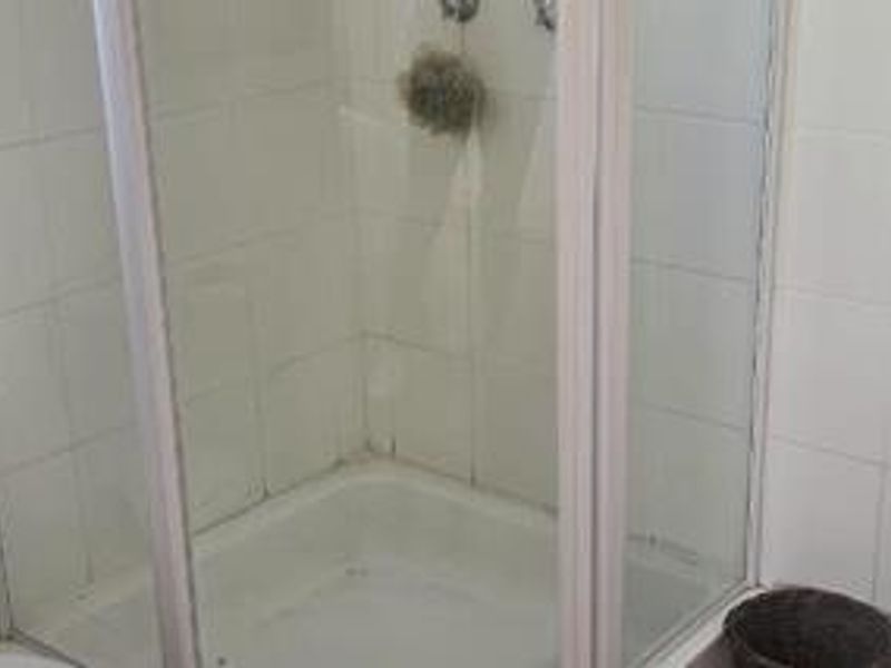 A functional bathroom shower enclosure featuring white wall tiles and a standard shower unit, requiring minor cosmetic updates to refresh the space.