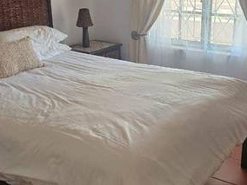 A bedroom featuring tiled flooring and a window fitted with security bars.