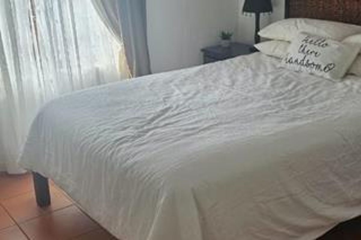 A bedroom featuring tiled flooring and natural light from a window with curtains.