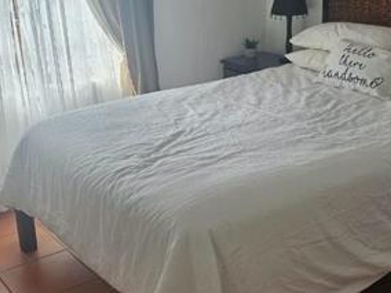 A bedroom featuring tiled flooring and natural light from a window with curtains.