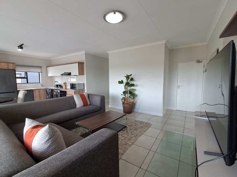 Open-plan living area featuring tiled flooring, integrated kitchen cabinetry with an extractor fan, and neutral wall finishes, creating a functional and cohesive living space.