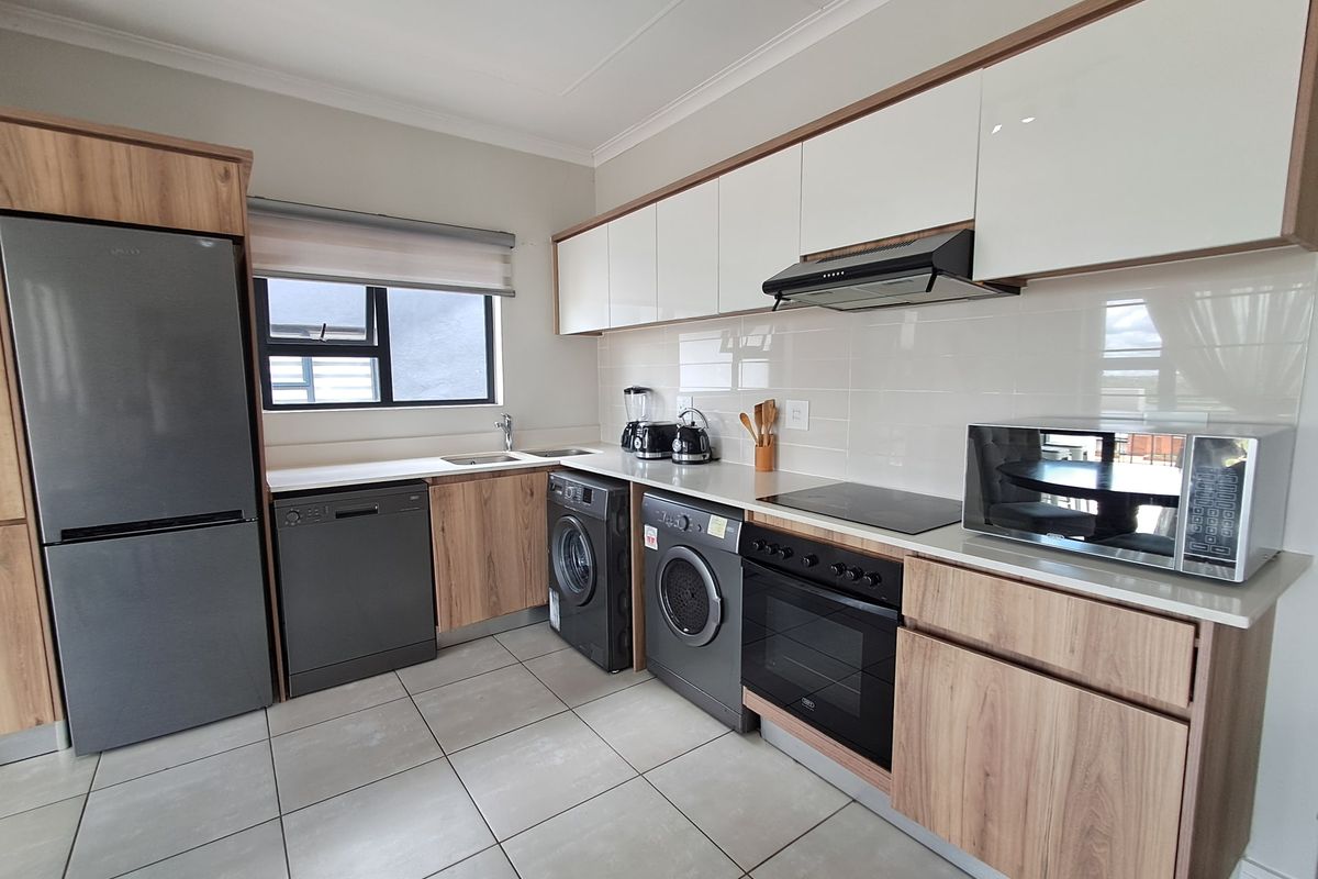 Modern kitchen featuring wood-grain and white cabinetry, stone countertops, integrated appliances, and tiled flooring in a clean, well-maintained condition.