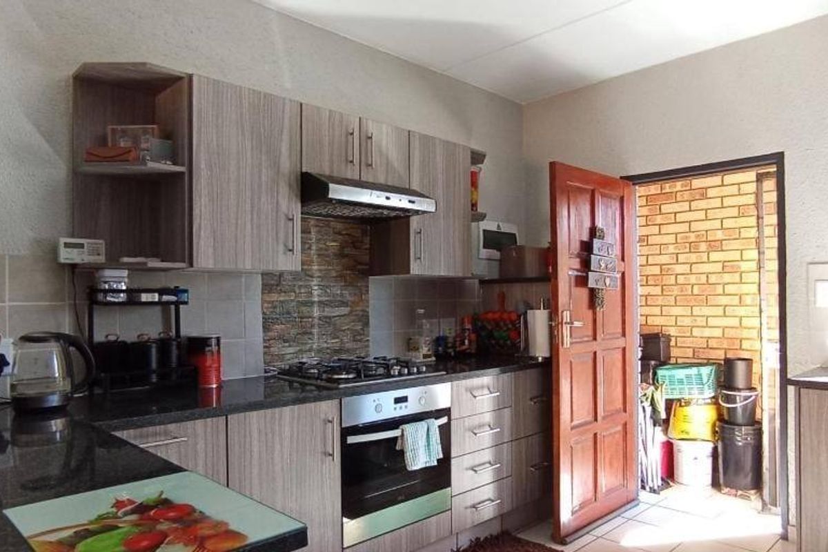 A functional kitchen featuring modern wood-grain cabinetry, granite countertops, a gas hob, and an integrated oven with a tiled backsplash.
