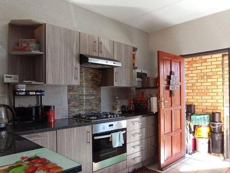 A functional kitchen featuring modern wood-grain cabinetry, granite countertops, a gas hob, and an integrated oven with a tiled backsplash.