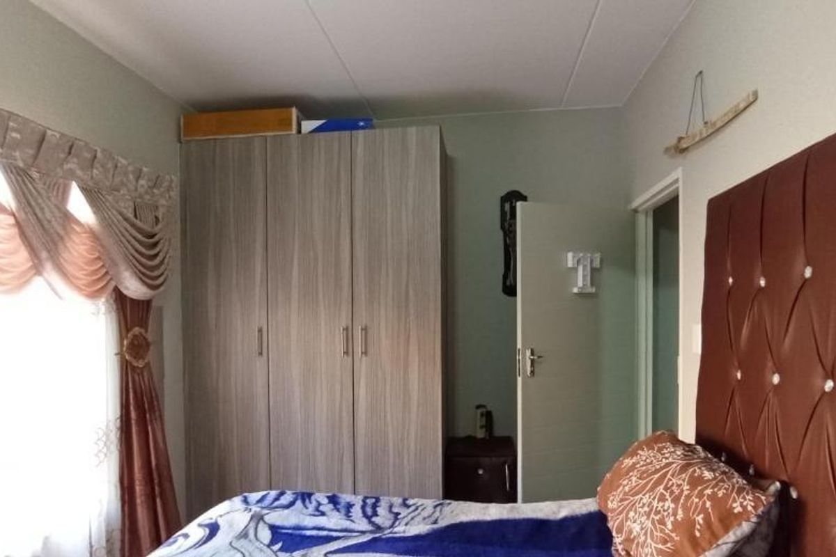A bedroom featuring a built-in wardrobe with wood-grain finish and a window with decorative pelmet.