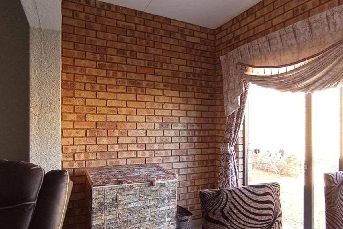 Living area featuring an exposed brick feature wall and sliding glass doors providing access to the exterior.