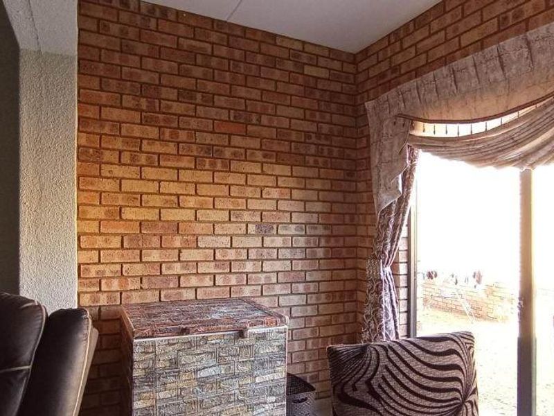 Living area featuring an exposed brick feature wall and sliding glass doors providing access to the exterior.