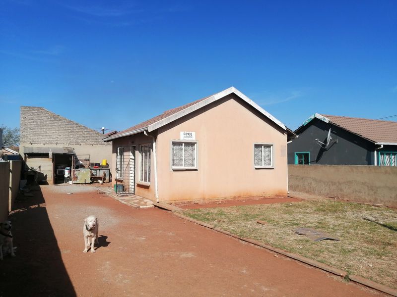 A single-story residential house featuring a tiled roof, security bars on windows, and a perimeter wall, set on a compact plot.