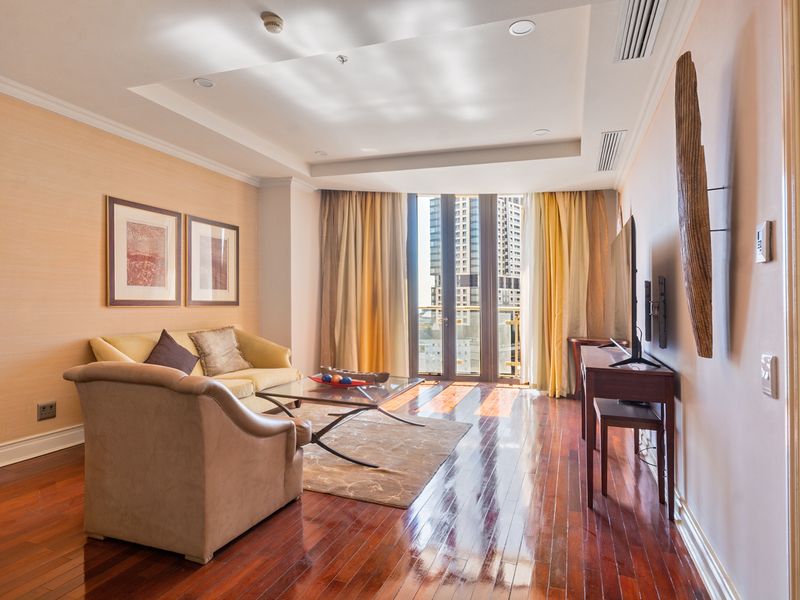 A well-maintained living room featuring polished hardwood flooring, recessed lighting, ducted air conditioning, and direct access to a balcony with city views.