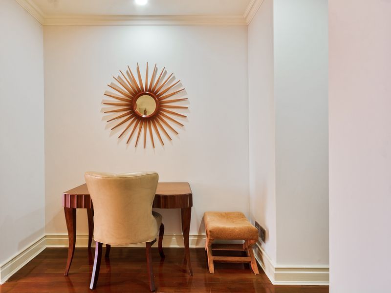 A compact office nook featuring polished hardwood flooring, crown molding, and crisp white walls, creating a clean and functional workspace.