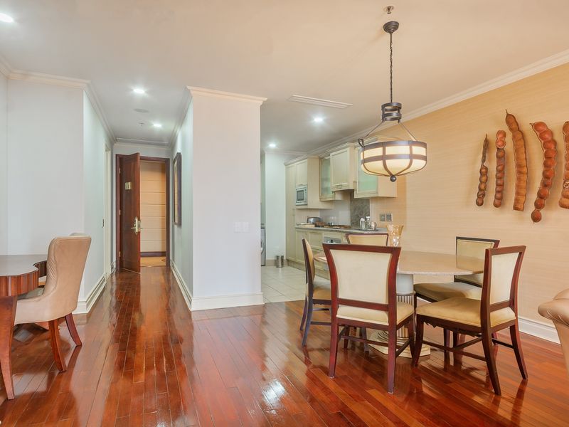 Open plan living and dining area featuring polished hardwood floors, crown molding, and a seamless transition into a functional kitchen space.