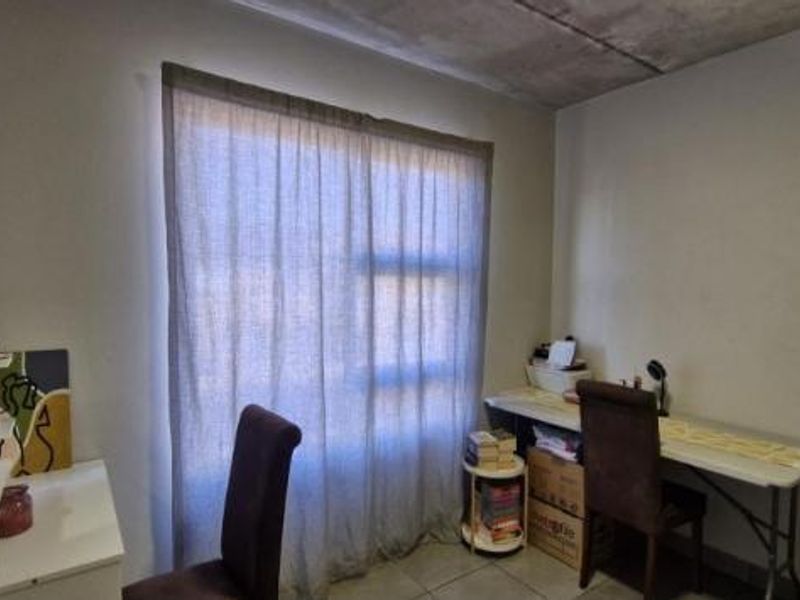 A bedroom featuring an exposed concrete ceiling and tiled flooring, offering a neutral space ready for personalization.