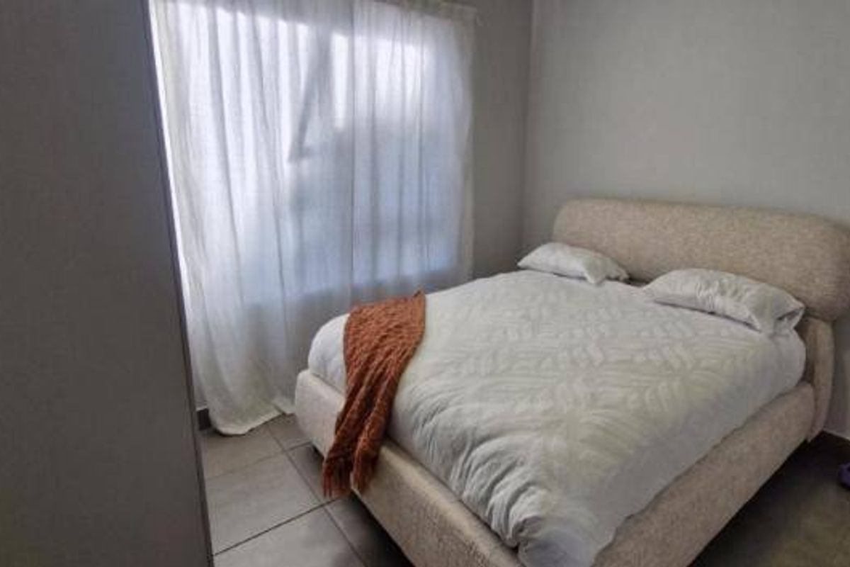 A simple bedroom featuring tiled flooring and a built-in cupboard, providing a functional and neutral space.